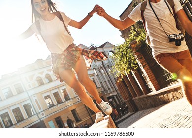 Romantic couple. Happy young couple holding hands and smiling while walking outdoors - Shutterstock ID 1169786500