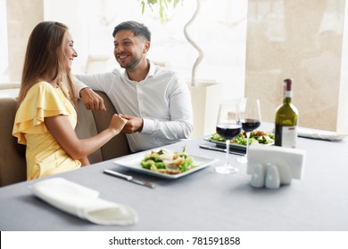 Romantic Couple Having Dinner For Two In Restaurant. Beautiful Happy People In Love Talking, Laughing, Flirting While Having Romantic Date With Wine And Food In Luxury Restaurant. High Quality Image.