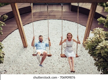Romantic couple is having fun outside. Enjoying spending time together on a swings.