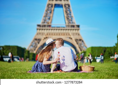 Romantic Couple Having Picnic On Grass With Wine And Fruits Near The Eiffel Tower In Paris