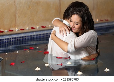 Romantic couple hugging in a pool  with candles and rose petals floating on the water