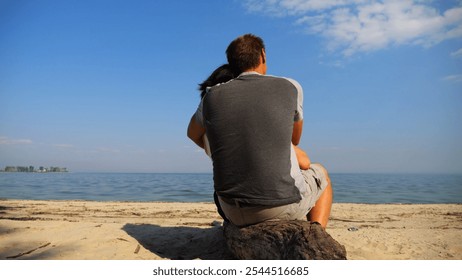 Romantic couple hugs during sitting on wooden log on the beach. Happy pair admiring a sea and landscape. Lovers spending time together at resort. Concept of vacation or holiday. Slow motion - Powered by Shutterstock