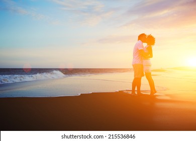 Romantic couple kissing on the beach at beautiful sunset on background,  valentines day background of couple in love, couple standing on the beach and watching the sunrise, couple kissing at sunset