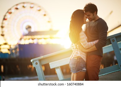 romantic couple kissing at sunset in fromt of santa monica ferris wheel.