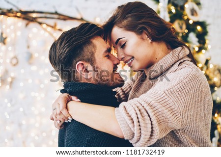 Romantic couple in love feeling happiness about their romance spending christmas eve together, woman and man enjoying perfect relationships and spending winter vacations in cozy home interior 