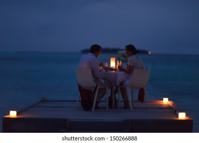 Romantic Couple  In Love Have Dinner In Outdoor Restaurant With Candles With Sea In Background