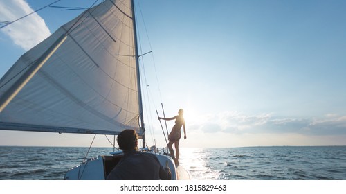 Romantic Couple In Love On Sail Boat At Sunset Under Sunlight On Yacht, A Man And A Woman Are Traveling On A Sailing Yacht.