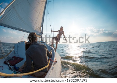 Romantic couple in love on sail boat at sunset under sunlight on yacht, A man and a woman are traveling on a sailing yacht.