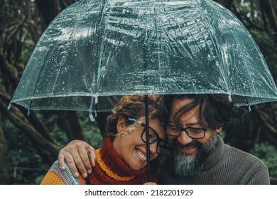 Romantic couple in love under umbrella in rainy day. Man and woman enjoy relationship and happiness together in winter autumn rain. Romance and people smiling end hugging at the park in leisure moment - Shutterstock ID 2182201929