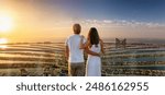 A romantic couple on a city vacation trip enjoys the panoramic sunset view of the Palm island at Dubai, UAE