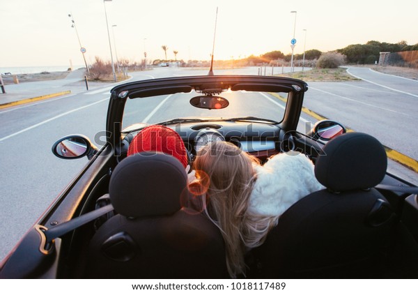 Romantic couple on honeymoon or amazing getaway\
travel trip in love, ride into sunset horizon on small red\
convertible cabriolet car with open roof with epic sunset flares,\
concept relationship\
goals