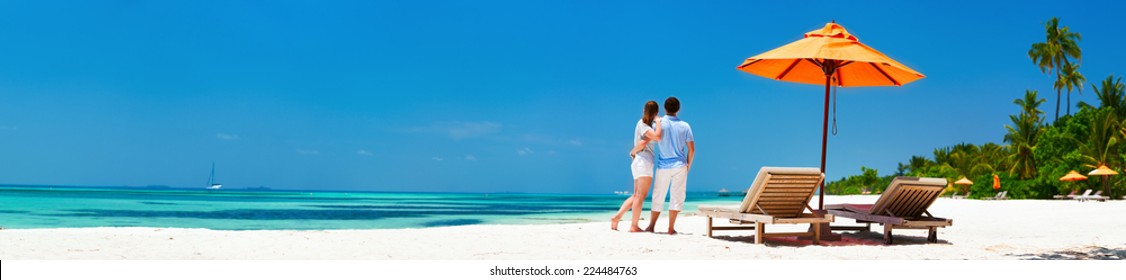 Romantic couple on a tropical beach during honeymoon vacation, wide panorama perfect for banners