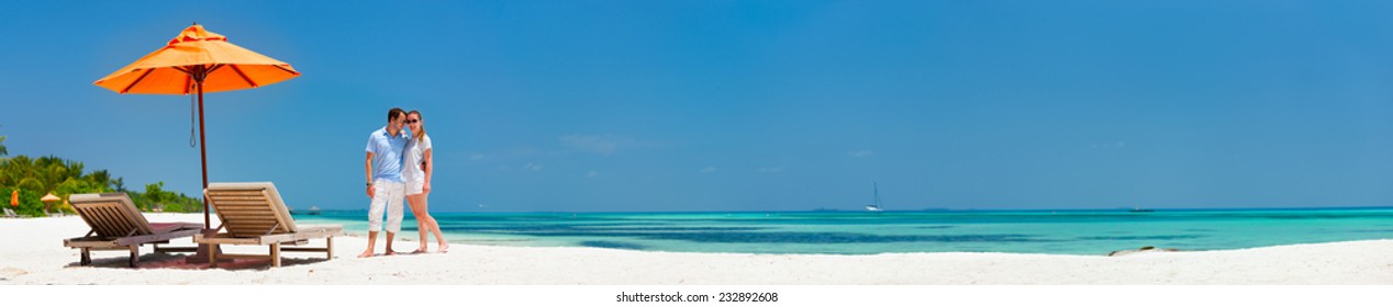 Romantic couple on a tropical beach during honeymoon vacation, super wide panorama perfect for banners
