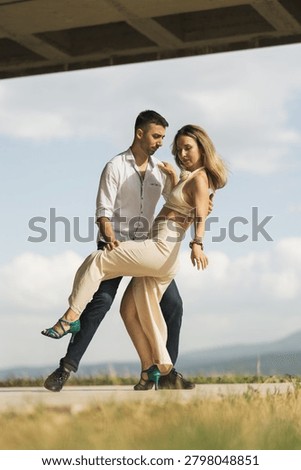 Romantic couple performing a dramatic tango outdoors, showcasing elegant fashion, close connection and fluid movement.