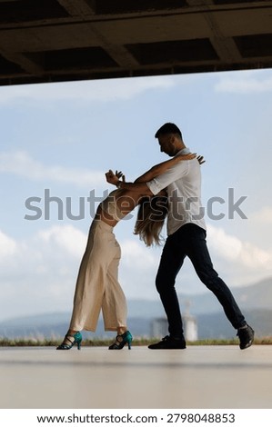 Romantic couple practicing a dramatic dip outdoors, showing connection, trust and graceful movement in urban surroundings.