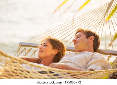 Romantic Couple Relaxing In Tropical Hammock At Sunset