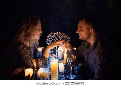 A romantic couple sharing a candlelit dinner. The dimly lit room creates an intimate atmosphere while the candles on the table add a touch of elegance to the setting. - Powered by Shutterstock