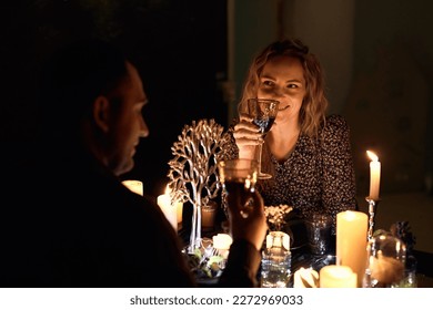 A romantic couple sharing a candlelit dinner. The dimly lit room creates an intimate atmosphere while the candles on the table add a touch of elegance to the setting. - Powered by Shutterstock