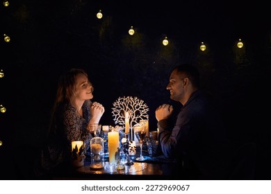 A romantic couple sharing a candlelit dinner. The dimly lit room creates an intimate atmosphere while the candles on the table add a touch of elegance to the setting. - Powered by Shutterstock