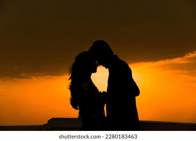 A romantic couple silhouette shadow close to each other and the sun set in the background - Powered by Shutterstock