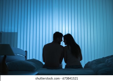 The romantic couple sit on the bed. night time