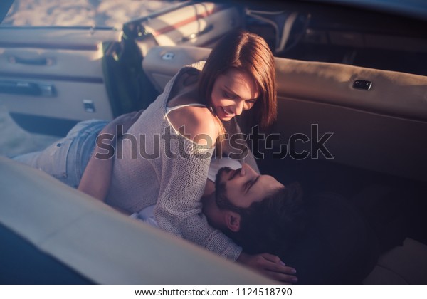 Romantic\
couple is sitting in green retro car on the beach. Handsome bearded\
man and attractive young woman in vintage classic car. Stylish love\
story. Hugging and kissing while being in\
car.