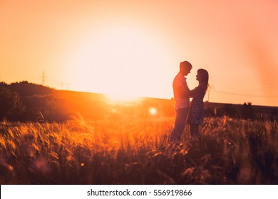 Casal romântico em pé e beijando no fundo verão prado pôr do sol