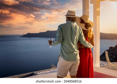 A romantic couple stands on the balkony and enjoys the beautiful summer sunset over the mediterranean sea with a glass of aperitif - Powered by Shutterstock