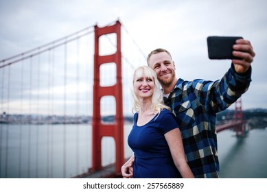 Romantic Couple Taking Selfie By Golden Gate Bridge With Film Grain Filter