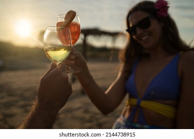 Romantic couple toast on sunset clinking wine and cocktail glasses in the beach