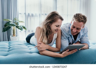 romantic couple using tablet pc while lying on the bed together - Powered by Shutterstock