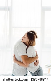 romantic couple in white t-shirts embracing at home