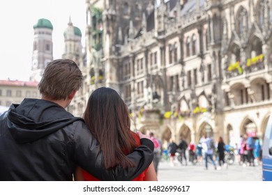 Romantic couple young woman and man hugging and looking to beautiful Frauenkirche church at Marienplatz town hall of Munich city, Germany together. Happy family on vacation in Europe with copy space