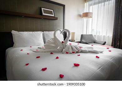 Romantic Cozy Boutique Hotel Room Getaway With Gorgeous Swan Towels Red Rose And Petals Spread On The Bed Waiting For Valentine Guests On Honeymoon Or Anniversary