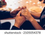 Romantic Date Concept. Selective focus on young loving couple holding hands spending time together at home or cafe, having dinner during date night, candles and food in blurred background