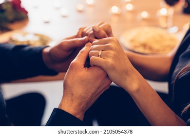 Romantic Date Concept. Selective Focus On Young Loving Couple Holding Hands Spending Time Together At Home Or Cafe, Having Dinner During Date Night, Candles And Food In Blurred Background