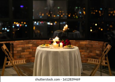 Romantic Date Dinner Concept. Served Table With Food And Burning Candles In Restaurant Interior At Night. No People