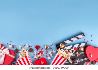 Romantic date on Valentine's Day February 14. Love movie marathon, date at cinema theater. Clapperboard, popcorn buckets, heart decor and chocolates on red background flat lay copy space - Powered by Shutterstock