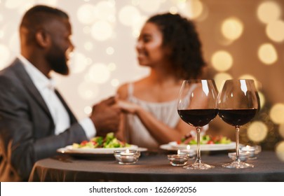 Romantic date at restaurant with candles and wine, black couple in love having festive dinner on Valentine's Day
