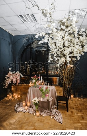 Romantic date. Table setting in restaurant. Luxury candlelight dinner setup table for couple on Valentine's day. Location decoration flowers, decor candles for surprise marriage proposal. Black window