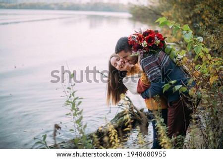 A romantic date, a walk in nature. Young couple of lovers together on the lake in early autumn. Man and woman walking by the water in yellow autumn foliage