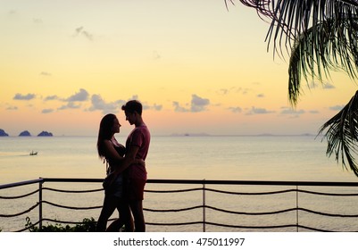 Romantic dating. Honey moon on tropical shore. Young loving couple standing together on terrace enjoying beautiful sea view. - Powered by Shutterstock