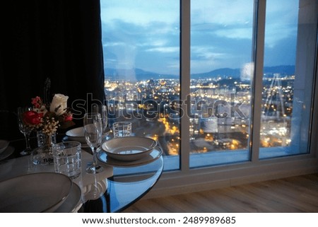 Romantic dining table setting next to window with night city view in a luxury apartment hotel room