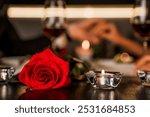 Romantic dinner date at night with focus on red rose and candles on the foreground. Defocused image of romantic relationship, dating. Valentine`s Day anniversary celebration