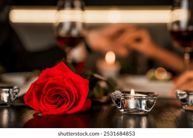 Romantic dinner date at night with focus on red rose and candles on the foreground. Defocused image of romantic relationship, dating. Valentine`s Day anniversary celebration - Powered by Shutterstock