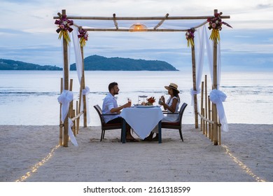Romantic dinner on the beach in Phuket Thailand, couple man and woman mid age Asian woman and European man having dinner on the beach in Thailand during sunset. 