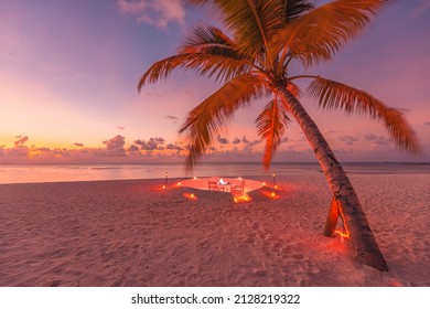 Romantic dinner on the beach with sunset, candles with palm leaves and sunset sky and sea. Amazing view, honeymoon or anniversary dinner landscape. Exotic island evening horizon, romance for a couple