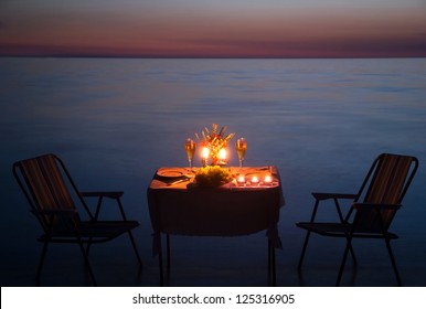 Romantic Dinner On The Sea Beach With Candles And Wine