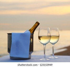 A Romantic Dinner In Summer On A Beach At Sunset With Two Glasses Of White Wine And A Wine Cooler