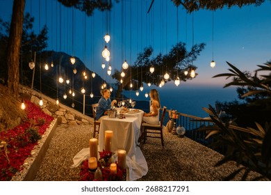 A romantic dinner table set for two, with a couple enjoying a sea view at sunset.

 - Powered by Shutterstock - Get 15% off with code: PIKWIZARD15